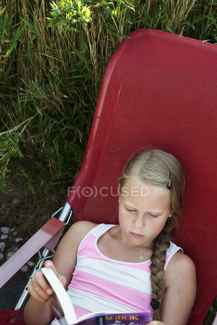 Lendo menina na espreguiçadeira, foco seletivo — Fotografia de Stock