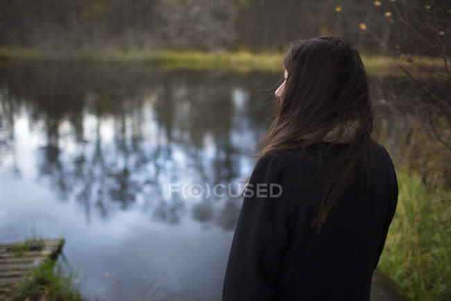 Mulher em pé na margem do rio e assistindo vista — Fotografia de Stock