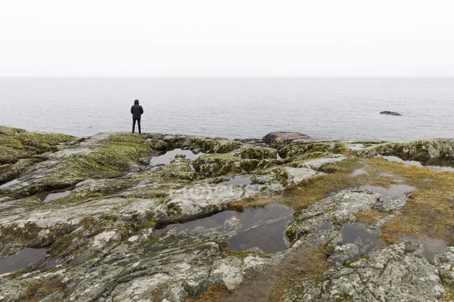 Homem em rochas por lago, foco seletivo — Fotografia de Stock