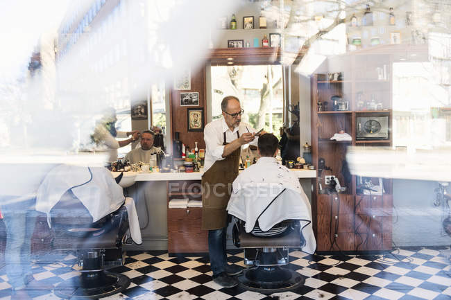 Blick aus dem Fenster: Friseure schneiden Kunden die Haare — Stockfoto