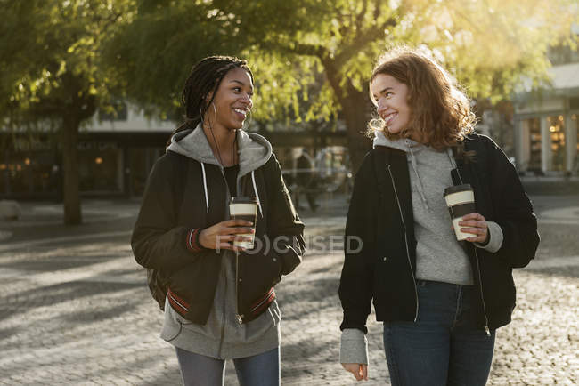 Smiling teenage girls with coffee cups — Stock Photo