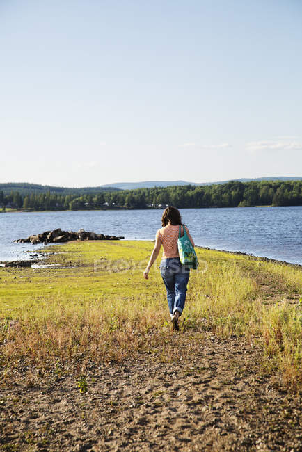 Donna che cammina sul lago, attenzione selettiva — Foto stock