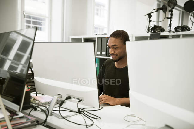 Hombre adulto medio que utiliza el ordenador en el cargo - foto de stock