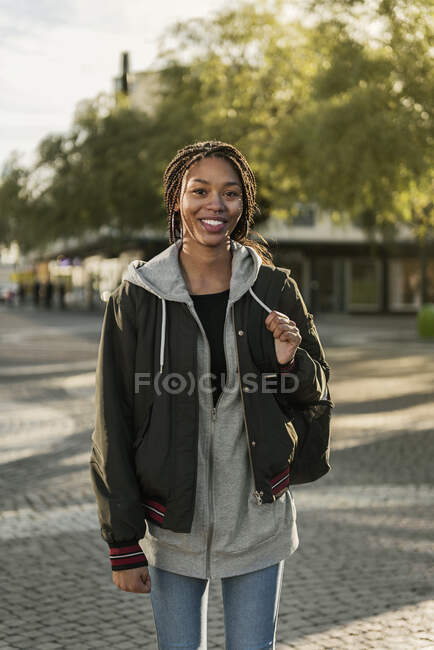 Retrato de niña adolescente sonriente que camina por la calle - foto de stock