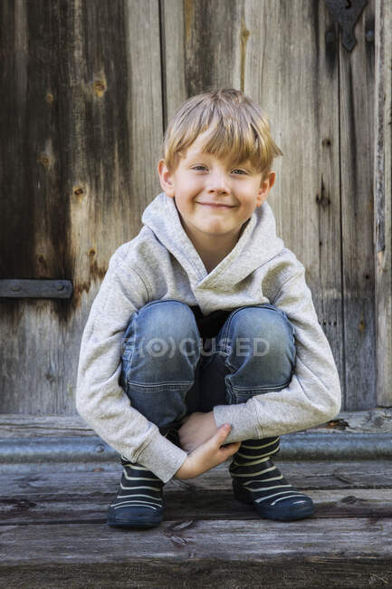 Portrait of boy crouching and smiling at camera — Stock Photo