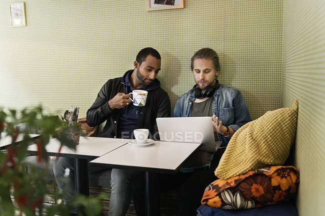 Jeunes hommes travaillant ensemble dans un café — Photo de stock