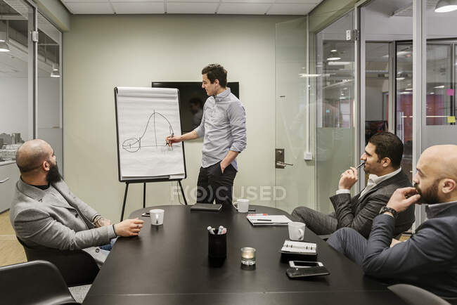 Hombres que discuten proyectos durante la reunión de negocios en el cargo - foto de stock