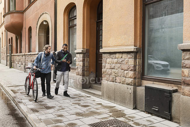 Young men walking on sidewalk, selective focus — Stock Photo