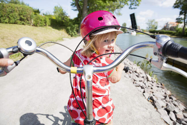 Adorable little girl in helmet cycling outdoors — Stock Photo