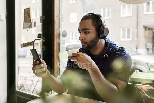 Молодий чоловік слухає музику в кафе, вибірковий фокус — стокове фото