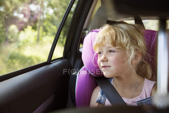 Adorable petite fille assise en voiture — Photo de stock