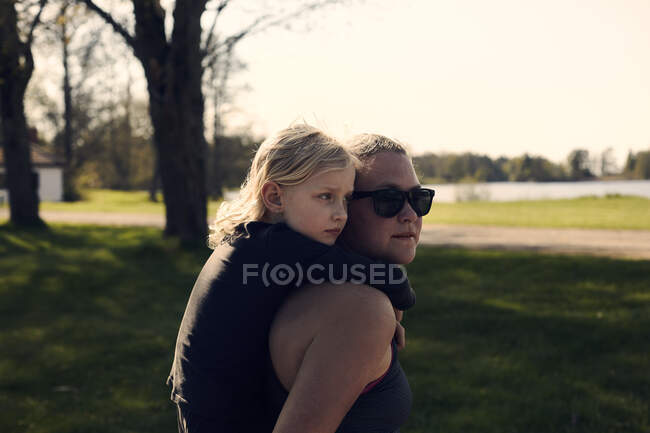 Mid adult woman giving girl piggyback in park — Stock Photo