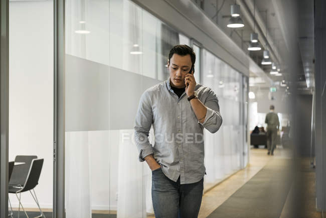 Молодой человек использует смартфон в коридоре — стоковое фото