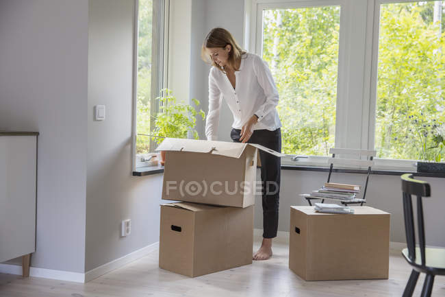 Frau packt in neuem Haus Kartons aus — Stockfoto