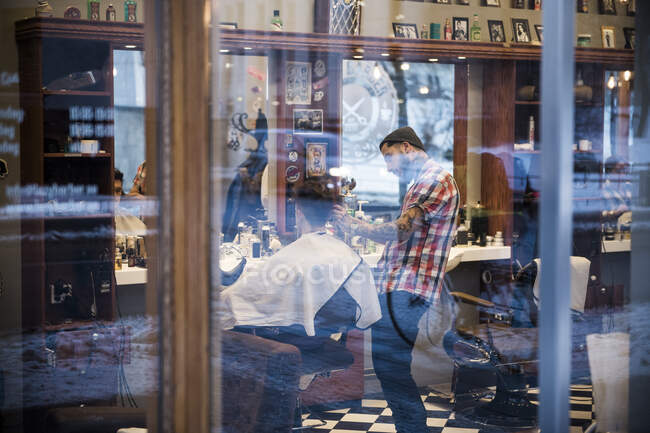 View through window of barber cutting customer hair — Stock Photo