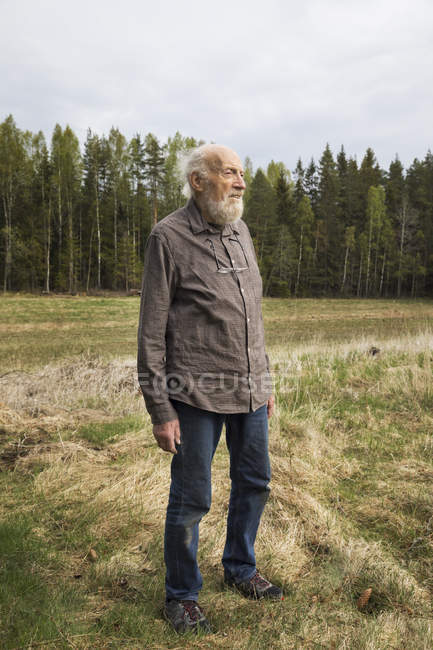 Homem sênior em pé no campo rural, foco seletivo — Fotografia de Stock