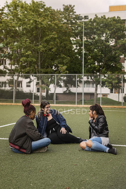 Chicas adolescentes sentadas en la cancha de tenis - foto de stock