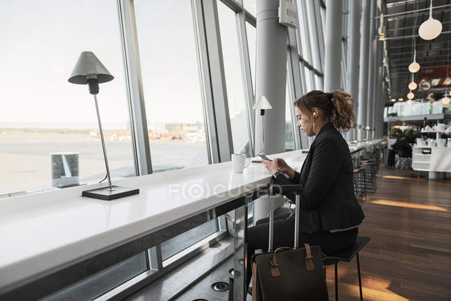 Frau benutzt Smartphone am Flughafen — Stockfoto