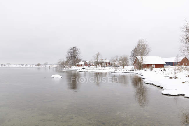 Casas na neve por lago, foco seletivo — Fotografia de Stock