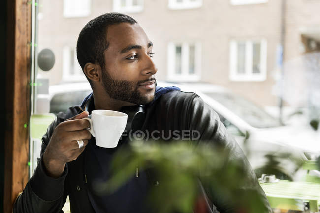 Молодой человек с чашкой кофе в кафе, избирательный фокус — стоковое фото