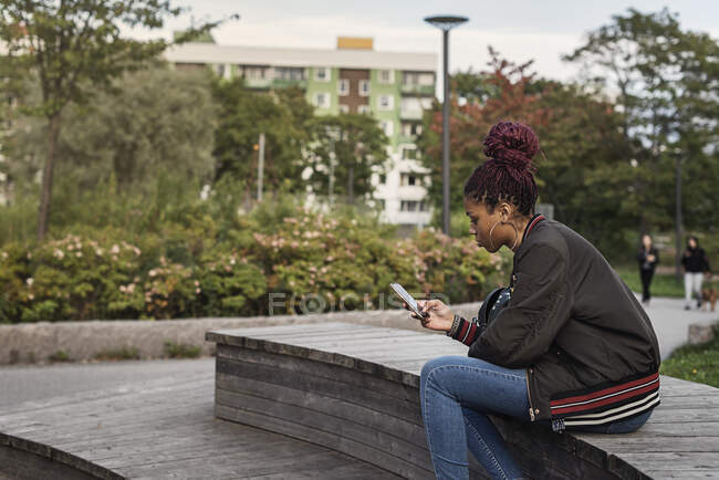 Вид сбоку красивой девочки-подростка с помощью смартфона в парке — стоковое фото