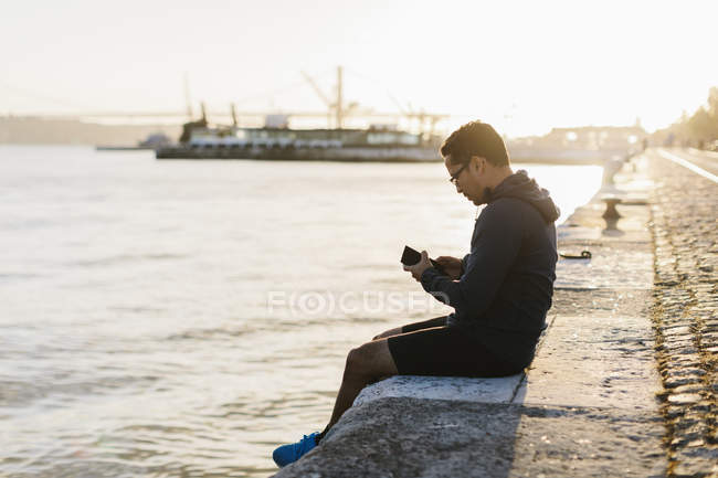 Mann benutzt Smartphone von tagus River, portugal — Stockfoto