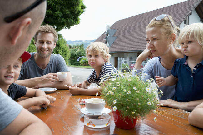Famiglia seduta al tavolo all'aperto — Foto stock