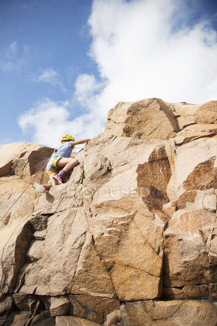 Девочка, лазающая по скалам, вид под низким углом — стоковое фото