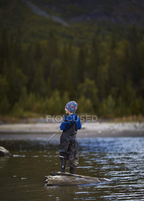 Adorable petit garçon pêchant en rivière — Photo de stock