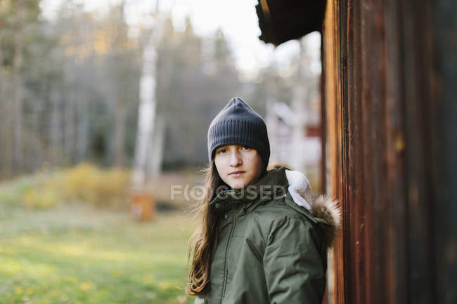 Menina vestindo gorro por parede de madeira — Fotografia de Stock