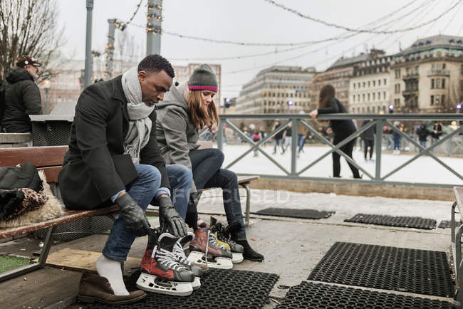 Couple putting on ice skates, selective focus — Stock Photo