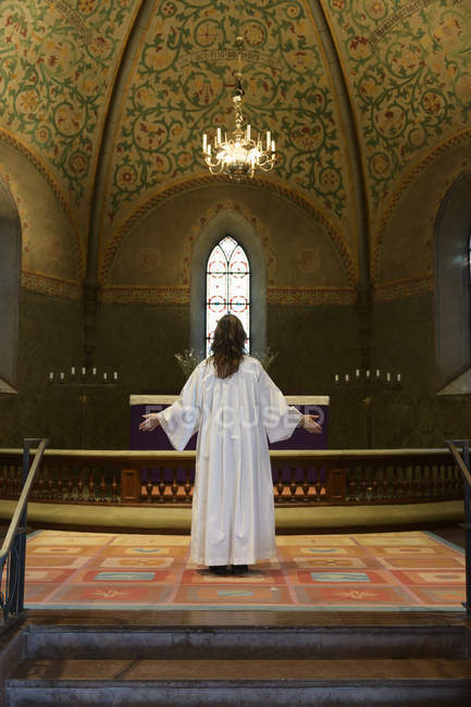 Sacerdote em vestes brancas em pé na capela-mor da igreja — Fotografia de Stock