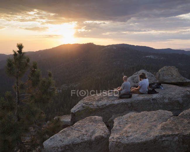 Homens na rocha ao pôr do sol no Parque Nacional Sequoia, na Califórnia — Fotografia de Stock