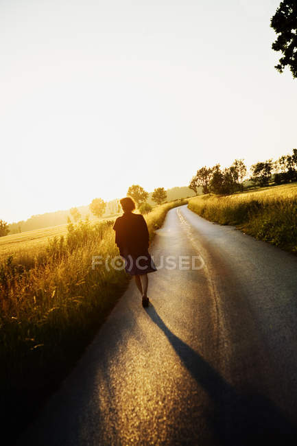 Mujer caminando por carretera, Gotland, Suecia - foto de stock