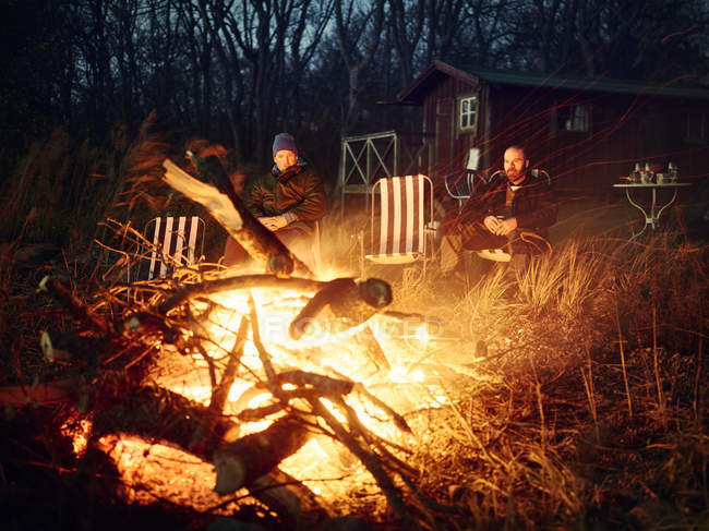 Men sitting by bonfire at sunset — Stock Photo
