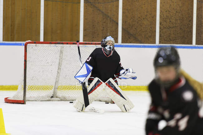 Menina no uniforme goleiro durante o treinamento de hóquei no gelo — Fotografia de Stock