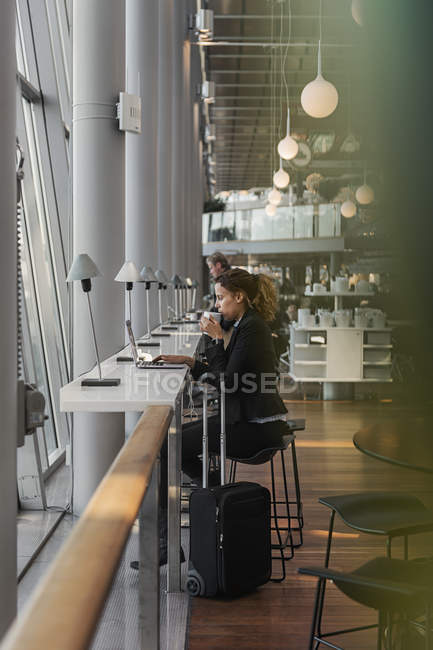 Femme utilisant un ordinateur portable à l'aéroport, mise au point sélective — Photo de stock