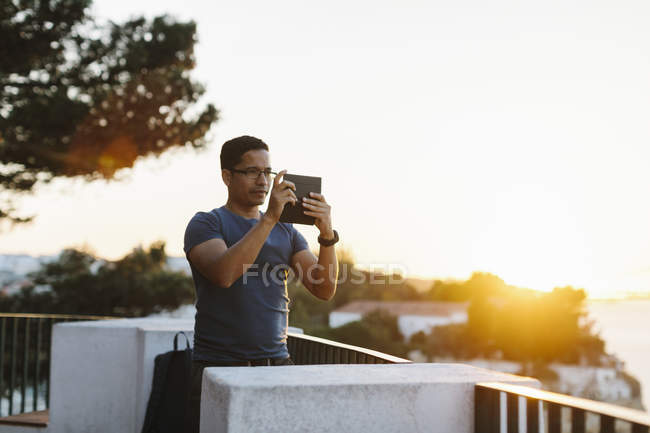 Людина фотографується зі смартфоном під час заходу сонця — стокове фото