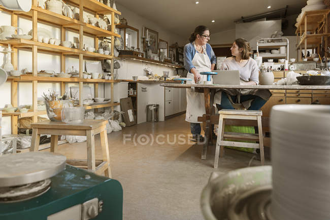 Женщины используют ноутбук в мастерской по керамике — стоковое фото