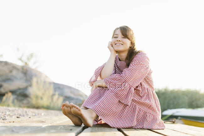 Jovem mulher vestindo vestido xadrez abraçando seus joelhos — Fotografia de Stock