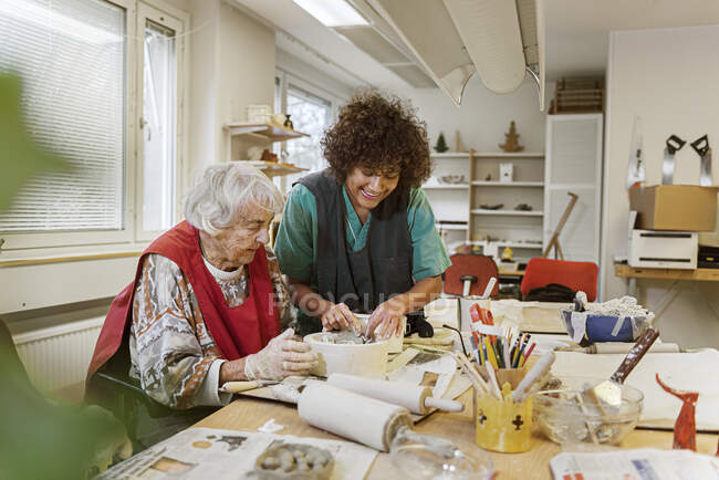 Mujer mayor haciendo cerámica en casa de descanso - foto de stock