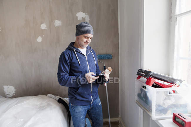 Взрослый мужчина смотрит на планшетный компьютер во время ремонта квартиры — стоковое фото