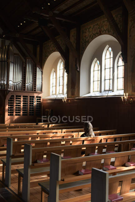 Priest sitting on pew in church, selective focus — Stock Photo