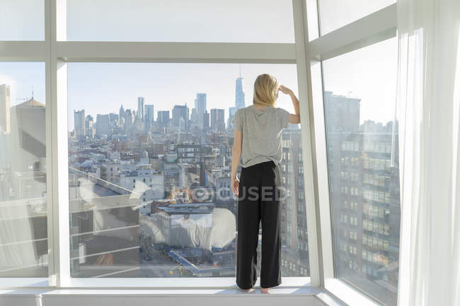 Adolescente menina blindagem olhos na frente da janela do apartamento da cidade — Fotografia de Stock
