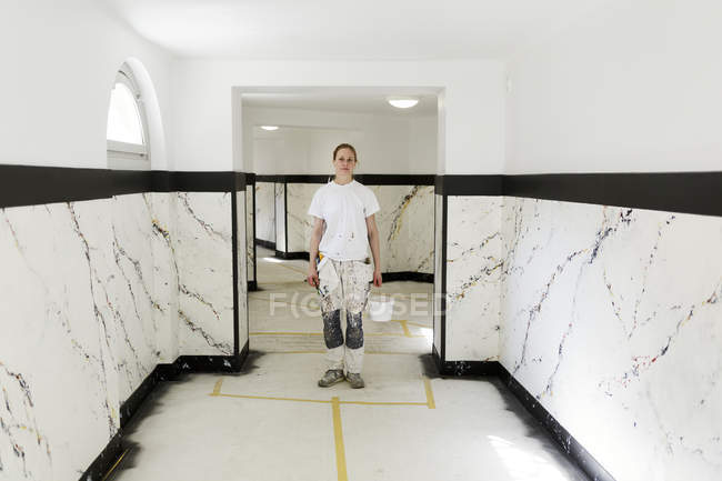 Pintor de pé no corredor do prédio de apartamentos — Fotografia de Stock