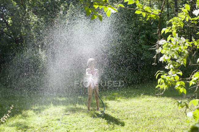 Menina brincando com mangueira no quintal, foco seletivo — Fotografia de Stock