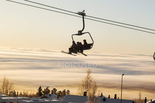 Silhouette of people on ski lift against sunset sky at wintertime — Stock Photo