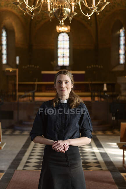 Портрет священника, стоящего и смотрящего на камеру в церкви — стоковое фото