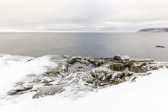 Nieve sobre rocas por lago, enfoque selectivo - foto de stock