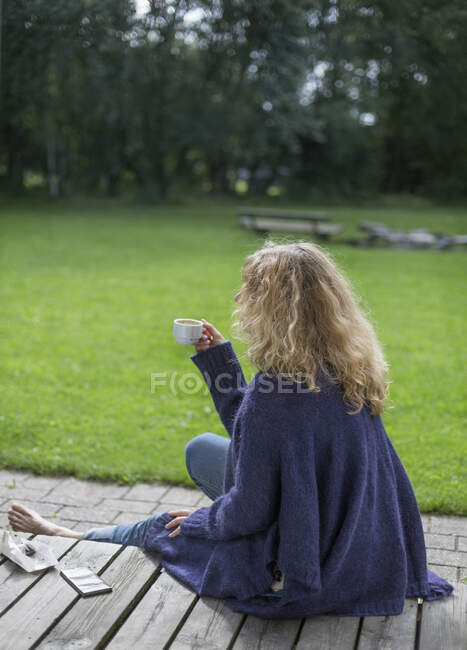 Женщина, пьющая кофе на палубе — стоковое фото